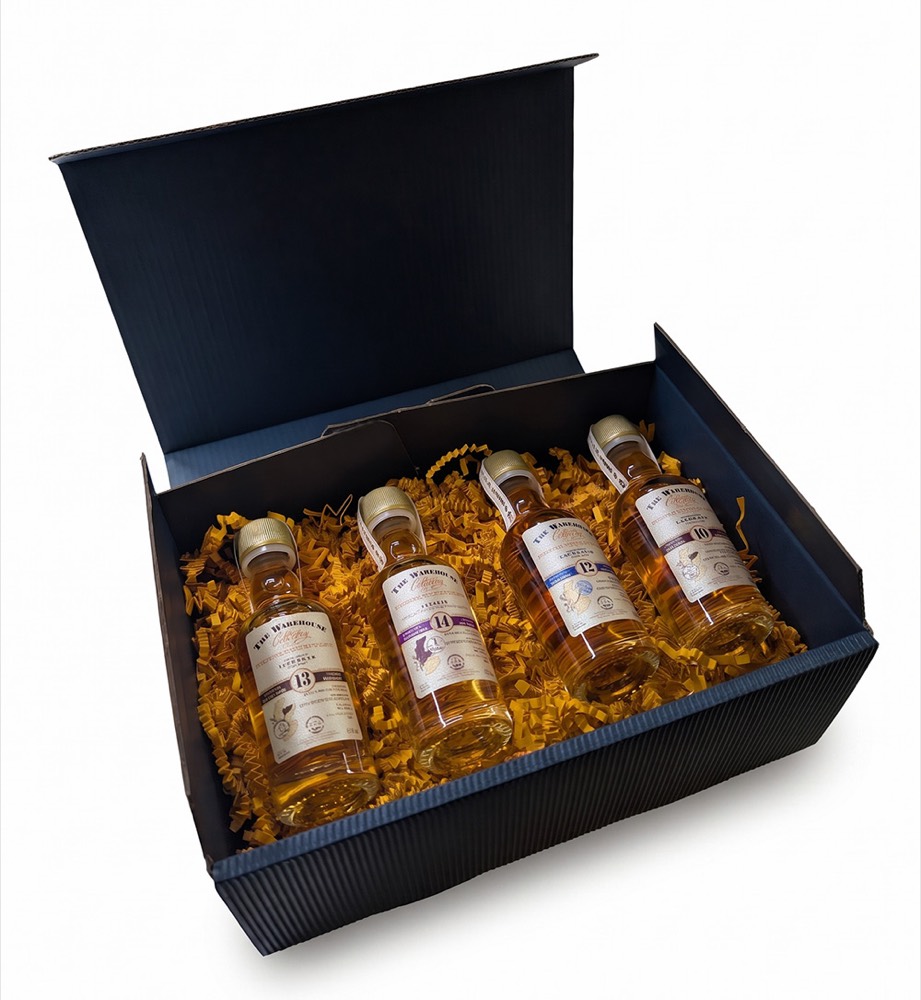 Geöffnete dunkelblaue Geschenkbox mit vier Whisky-Miniaturen in Holzwolle